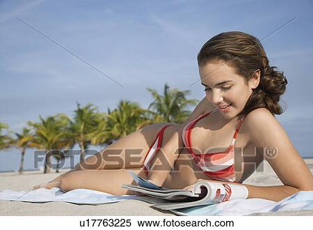 Teenage girl (16-17) reading magazine lying on beach View Large Photo Image Stock Photography - Teenage girl (16-17) reading magazine lying on beach. Fotosearch