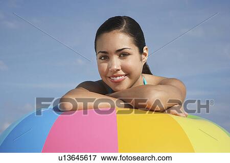 Stock Photo - Teenage girl (16-17) sitting leaning on beach ball close up portrait. Fotosearch