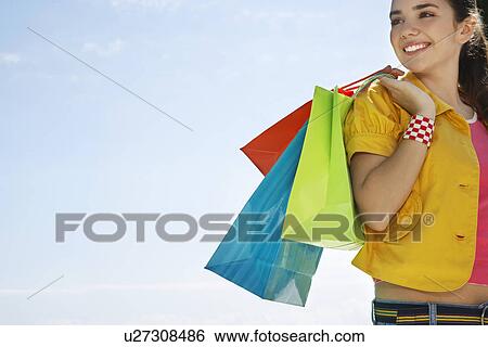 Stock Photograph - Teenage girl carrying shopping bags outdoors. Fotosearch