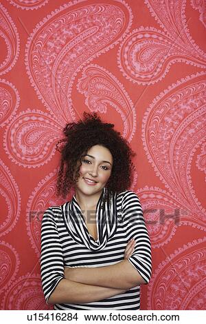 Picture - Teenage Girl in standing arms crossed in front of Colourful Wallpaper. Fotosearch