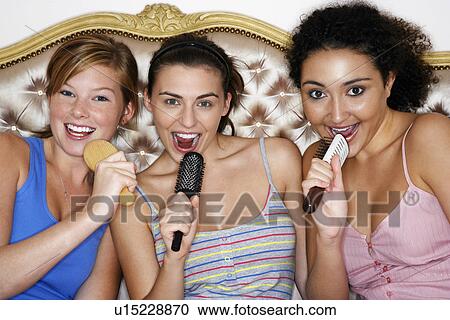 Teenage Girls using brushes as microphones singing at Slumber Party View Large Photo Image Stock Image - Teenage Girls using brushes as microphones singing at Slumber Party. Fotosearch