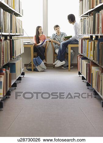 Stock Photograph - Teenagers doing homework in library. Fotosearch