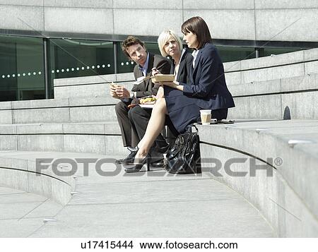 Three business people sitting on stairs outdoors talking side view View Large Photo Image Picture - Three business people sitting on stairs outdoors talking side view. Fotosearch