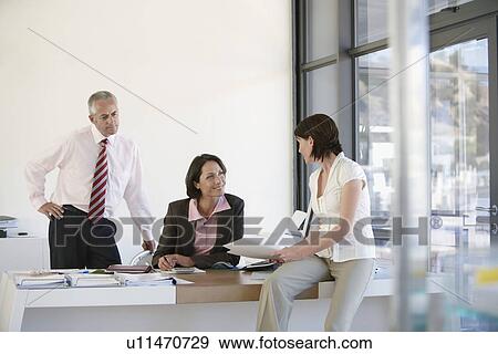 Stock Photo - Three businesspeople in office having business meeting.. Fotosearch