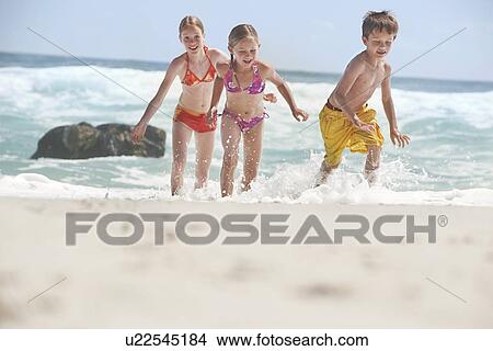 Three children (5-6 7-9 10-12) running on beach View Large Photo Image Picture - Three children (5-6 7-9 10-12) running on beach. Fotosearch