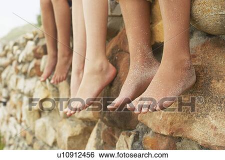 Three children (5-6 7-910-12) sitting in row on stone wall low section View Large Photo Image Stock Photograph - Three children (5-6 7-910-12) sitting in row on stone wall low section. Fotosearch