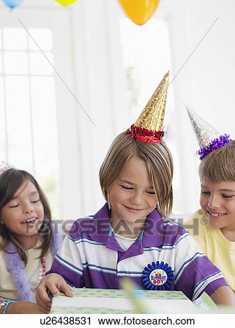 Three children (7-12) at birthday party one boy opening present View Large Photo Image Stock Image - Three children (7-12) at birthday party one boy opening present. Fotosearch