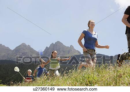 Three children (7-9) holding butterfly nets running through field with parents low angle view. View Large Photo Image Stock Photo - Three children (7-9) holding butterfly nets running through field with parents low angle view.. Fotosearch