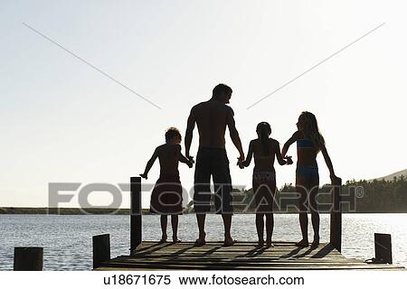 Three children (7-9) holding hands with father standing on edge of dock back view. View Large Photo Image Stock Photography - Three children (7-9) holding hands with father standing on edge of dock back view.. Fotosearch