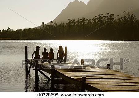 Three children (7-9) sitting on edge of dock back view. View Large Photo Image Stock Photography - Three children (7-9) sitting on edge of dock back view.. Fotosearch