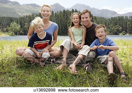 Three children (7-9) sitting outdoors on grass with parents family portrait. View Large Photo Image Stock Photo - Three children (7-9) sitting outdoors on grass with parents family portrait.. Fotosearch