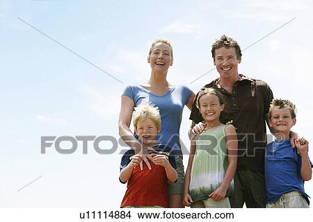 Picture - Three children (7-9) with parents outdoors low angle portrait.. Fotosearch