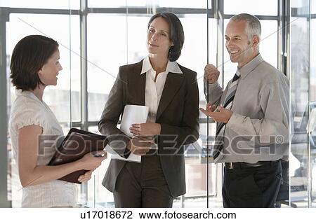 Three office workers standing in office talking. View Large Photo Image Stock Image - Three office workers standing in office talking.. Fotosearch