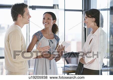 Three office workers standing in office talking. View Large Photo Image Stock Photo - Three office workers standing in office talking.. Fotosearch