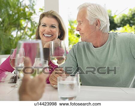 Three people sitting at verandah holding wine glasses View Large Photo Image Stock Photo - Three people sitting at verandah holding wine glasses. Fotosearch