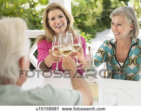 Three people toasting with wine glasses sitting at verandah table View Large Photo Image Stock Image - Three people toasting with wine glasses sitting at verandah table. Fotosearch