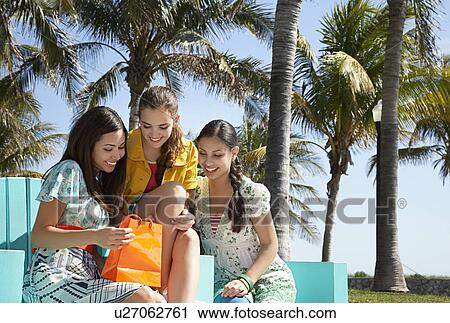 Three teenage girls (16-17) sitting in park looking at shopping bags View Large Photo Image Stock Image - Three teenage girls (16-17) sitting in park looking at shopping bags. Fotosearch