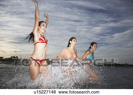Stock Photo - Three teenage girls (17-19) splashing in sea. Fotosearch