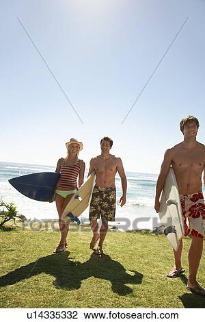 Three young people with surf board walking away from sea full length View Large Photo Image Stock Image - Three young people with surf board walking away from sea full length. Fotosearch