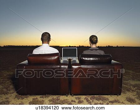 Two business people sitting in armchairs in open plain at sunset back view View Large Photo Image Stock Image - Two business people sitting in armchairs in open plain at sunset back view. Fotosearch