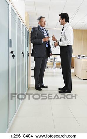 Two businessmen talking in office corridor View Large Photo Image Picture - Two businessmen talking in office corridor. Fotosearch