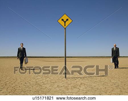 Two businessmen with briefcases walking towards road sign in desert full length View Large Photo Image Stock Image - Two businessmen with briefcases walking towards road sign in desert full length. Fotosearch
