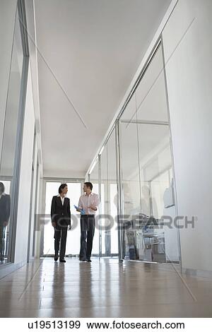 Two businesspeople walking in hallway of office low angle view. View Large Photo Image Stock Photo - Two businesspeople walking in hallway of office low angle view.. Fotosearch
