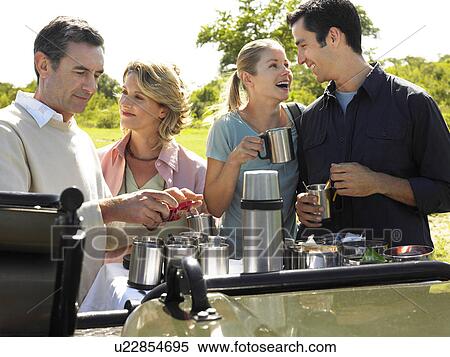 Two couples having picnic trees in background View Large Photo Image Stock Photography - Two couples having picnic trees in background. Fotosearch