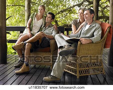 Two couples sitting on terrace smiling one holding book View Large Photo Image Stock Photo - Two couples sitting on terrace smiling one holding book. Fotosearch