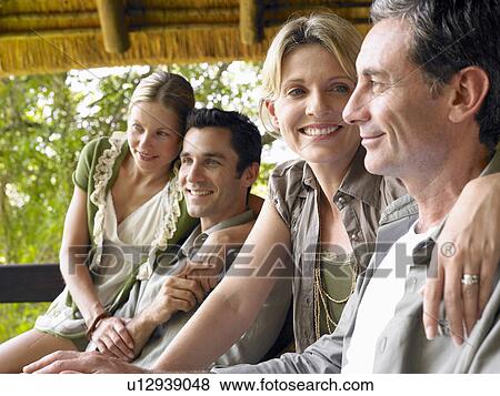 Stock Photo - Two couples sitting on terrace smiling. Fotosearch