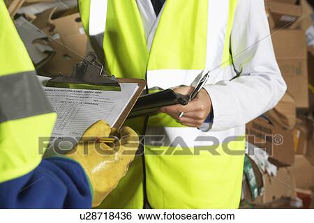 Stock Photograph - Two factory workers holding clipboards mid section. Fotosearch