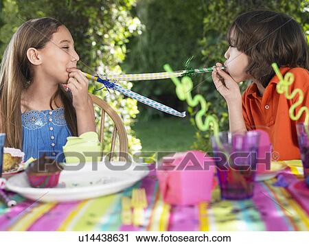 Two girls (10-12) blowing party puffers at birthday party View Large Photo Image Stock Image - Two girls (10-12) blowing party puffers at birthday party. Fotosearch