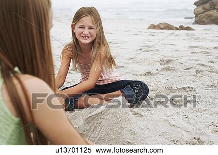 Two girls (10-12) playing in sand on beach focus on girl in background View Large Photo Image Stock Photography - Two girls (10-12) playing in sand on beach focus on girl in background. Fotosearch