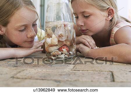 Two girls (7-9 10-12) looking at shells in jar close-up View Large Photo Image Stock Photo - Two girls (7-9 10-12) looking at shells in jar close-up. Fotosearch