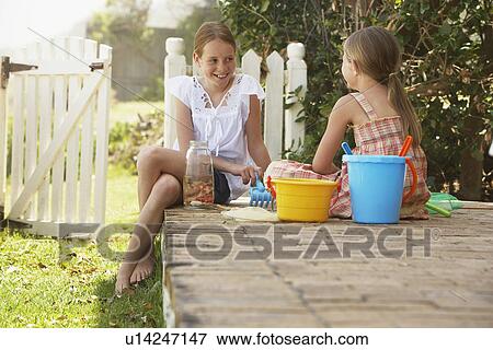 Stock Photo - Two girls (7-9 10-12) playing on garden. Fotosearch