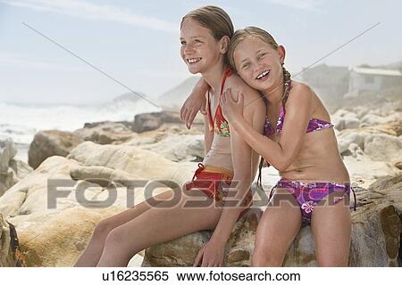 Two girls (7-9 10-12) sitting on rock on beach View Large Photo Image Stock Photography - Two girls (7-9 10-12) sitting on rock on beach. Fotosearch