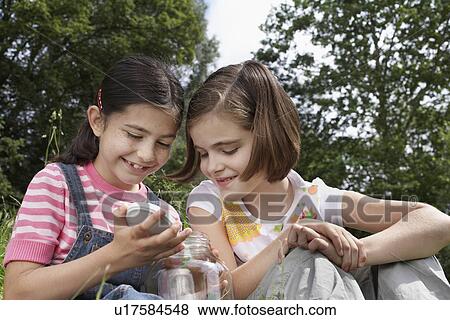 Two girls (7-9) examining jar of insects outdoors View Large Photo Image Stock Photo - Two girls (7-9) examining jar of insects outdoors. Fotosearch