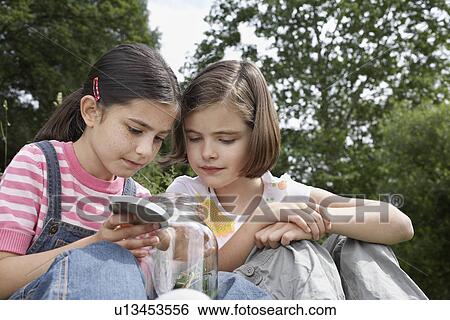 Two girls (7-9) examining jar of insects outdoors View Large Photo Image Stock Photograph - Two girls (7-9) examining jar of insects outdoors. Fotosearch