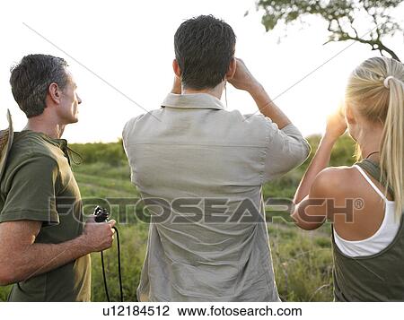 Two men and woman looking through binoculars back view View Large Photo Image Stock Image - Two men and woman looking through binoculars back view. Fotosearch