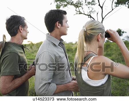 Stock Image - Two men and woman with binoculars side view. Fotosearch