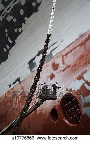 Two men in cherry picker working at ship in dry dock low angle view View Large Photo Image Stock Photograph - Two men in cherry picker working at ship in dry dock low angle view. Fotosearch
