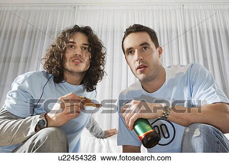 Two men watching television having pizza and beer low angle view View Large Photo Image Stock Photo - Two men watching television having pizza and beer low angle view. Fotosearch