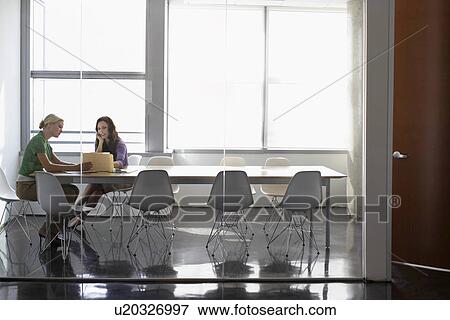 Stock Photo - Two office workers sitting in conference room. Fotosearch