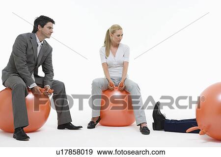 Two people sitting on space hoppers looking at fallen man against white background View Large Photo Image Stock Photo - Two people sitting on space hoppers looking at fallen man against white background. Fotosearch