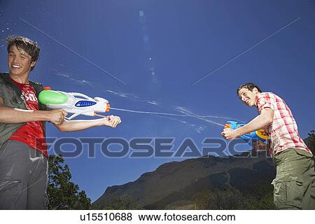 Two teenage boys (16-17 years) fighting with squirt guns in mountains View Large Photo Image Stock Photo - Two teenage boys (16-17 years) fighting with squirt guns in mountains. Fotosearch