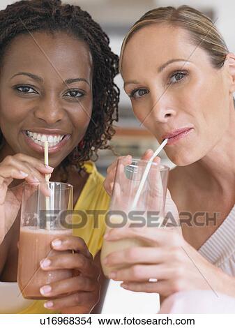 Picture - Two women drinking milkshake portrait. Fotosearch