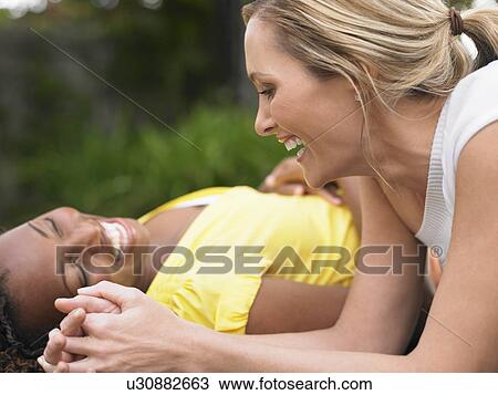 Two women lying down and laughing side view View Large Photo Image Stock Image - Two women lying down and laughing side view. Fotosearch
