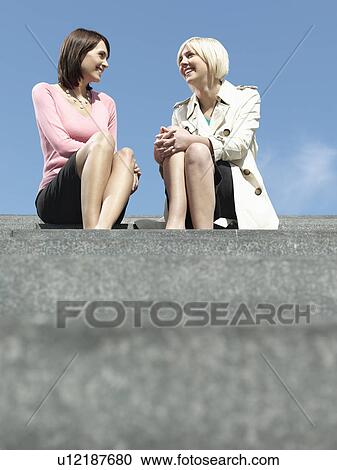 Two women sitting and talking on stairs outdoors low angle view View Large Photo Image Stock Image - Two women sitting and talking on stairs outdoors low angle view. Fotosearch