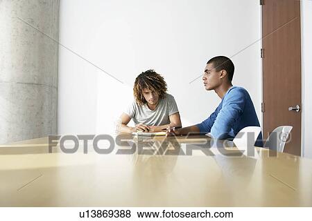 Stock Photo - Two young men sitting at conference table. Fotosearch