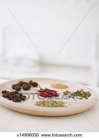 Stock Image - Variety of spices on wooden serving platter. Fotosearch